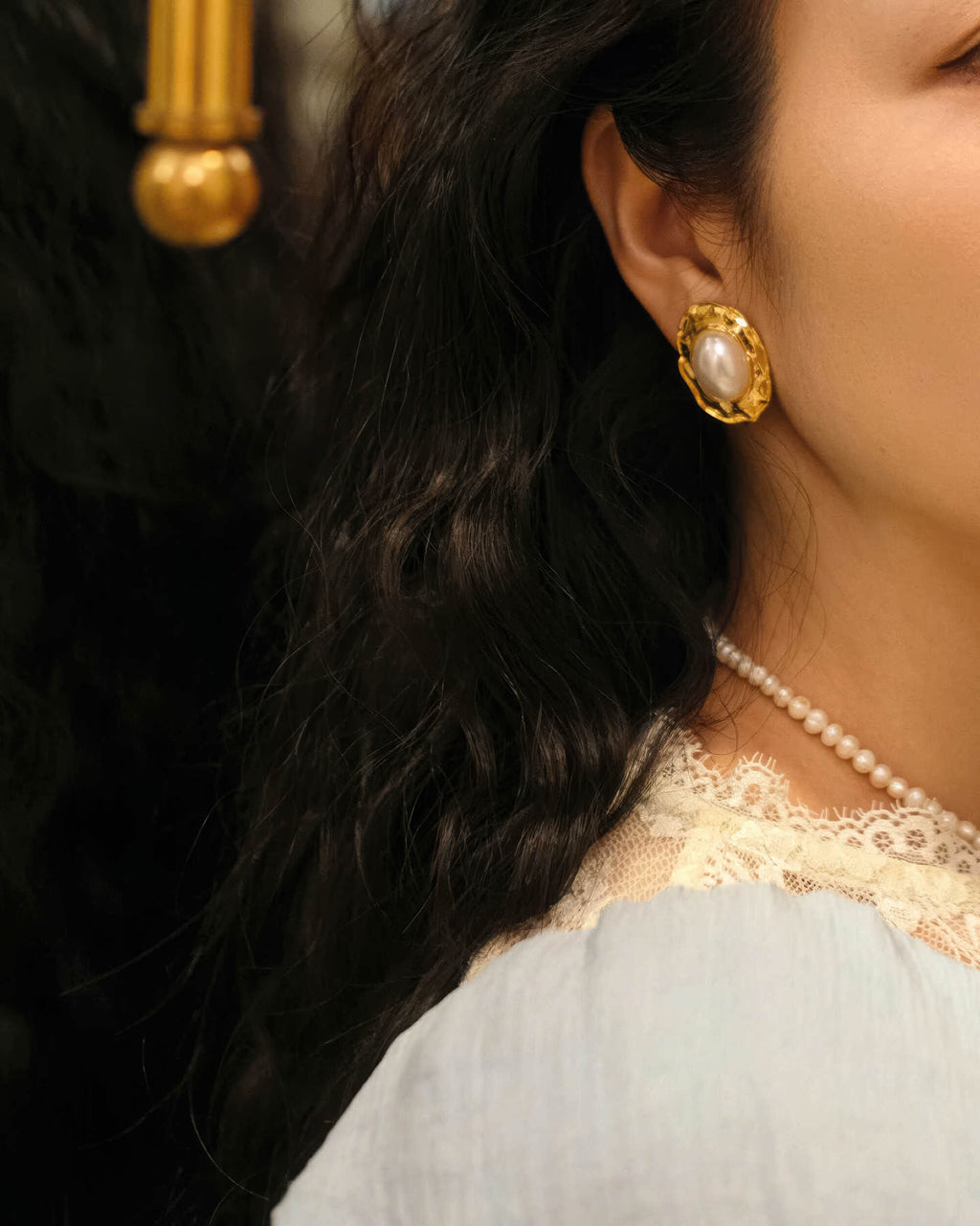 Side profile of the large gold-rimmed pearl earrings, emphasizing the secure fit and high-quality craftsmanship.