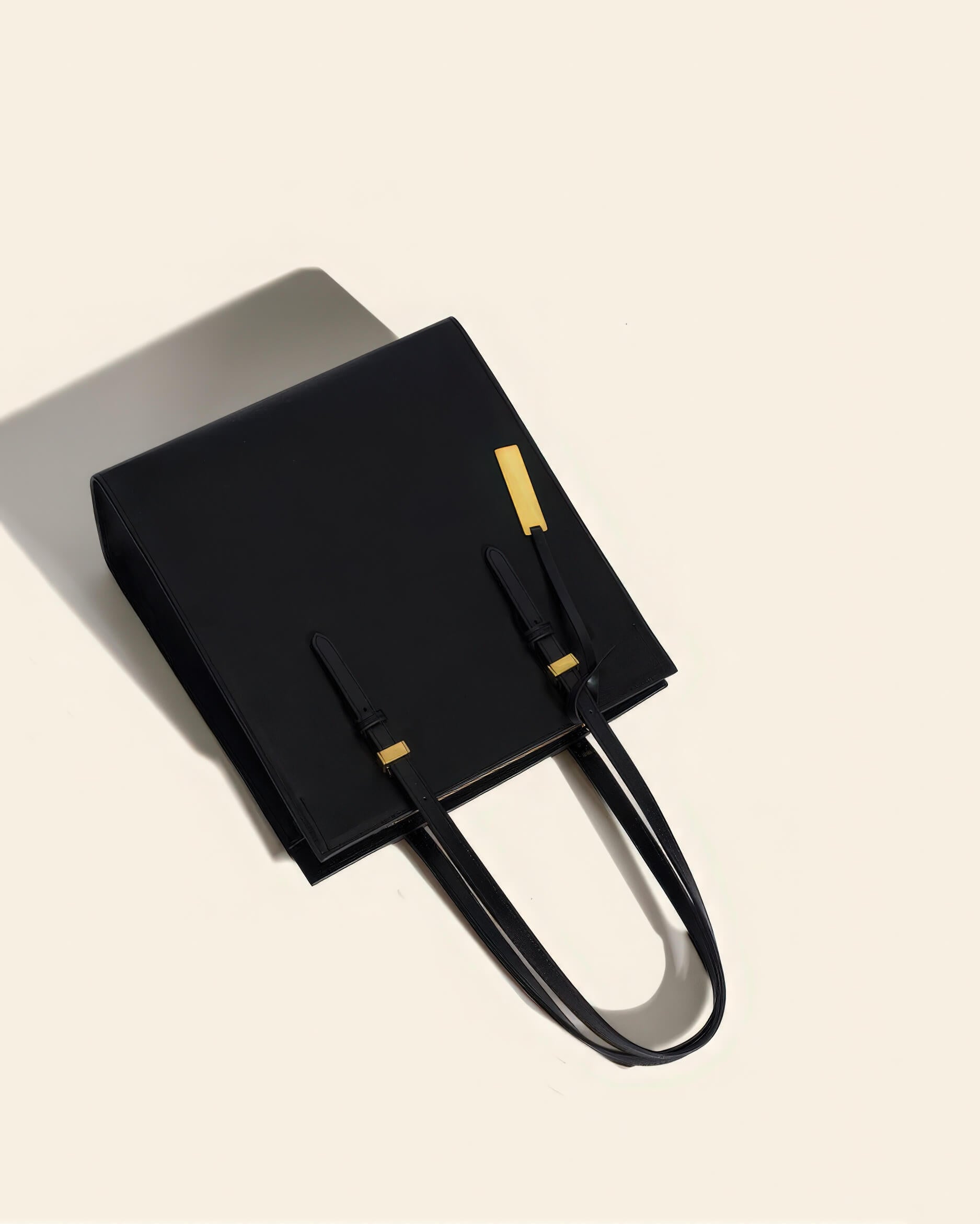 Top-down view of a black leather handbag featuring premium stitching and adjustable buckle straps.