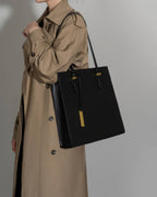 Professional woman carrying a large black leather tote bag, ideal for office or daily use.