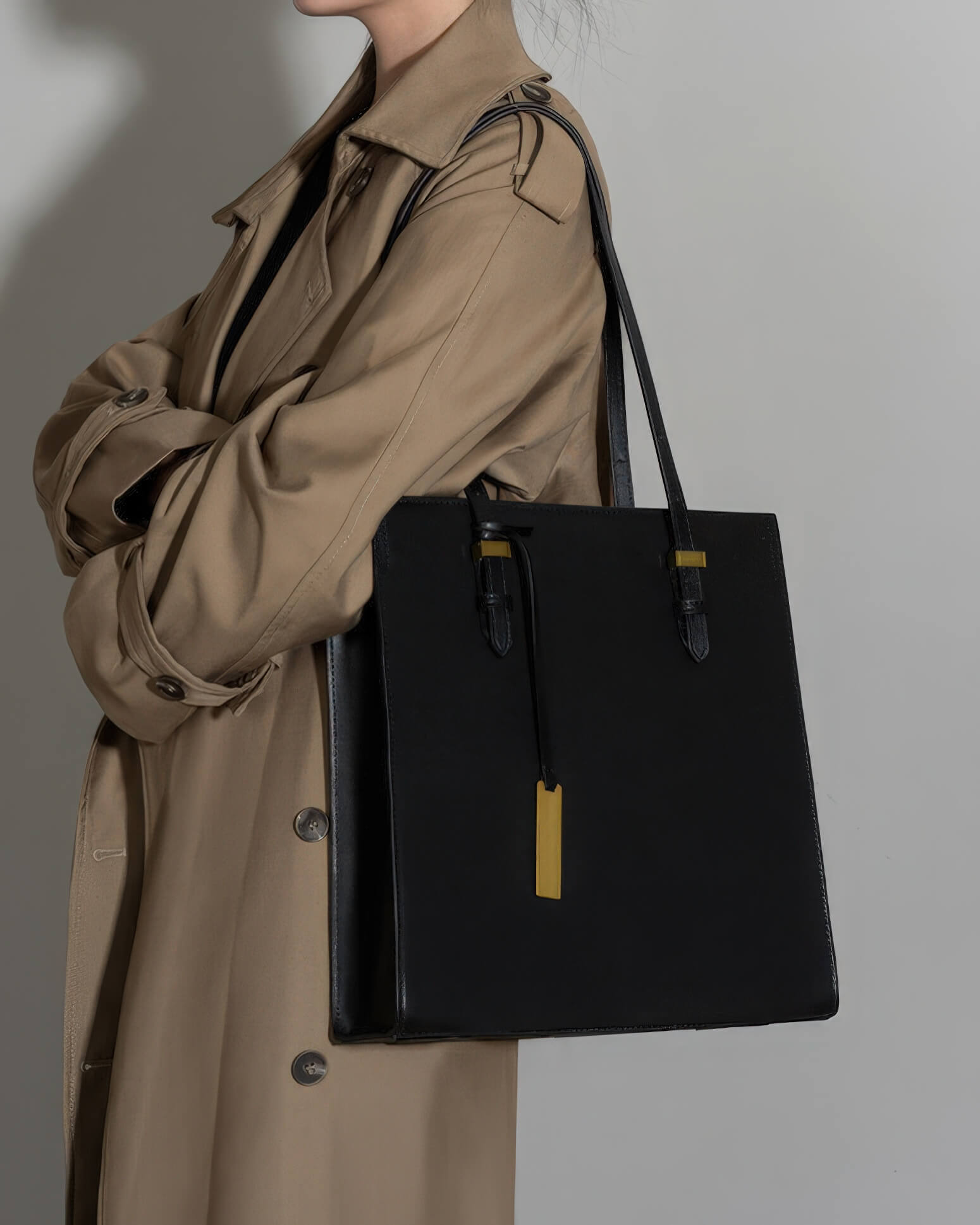 Side view of a woman wearing a black leather tote bag with a medium strap length over her shoulder.
