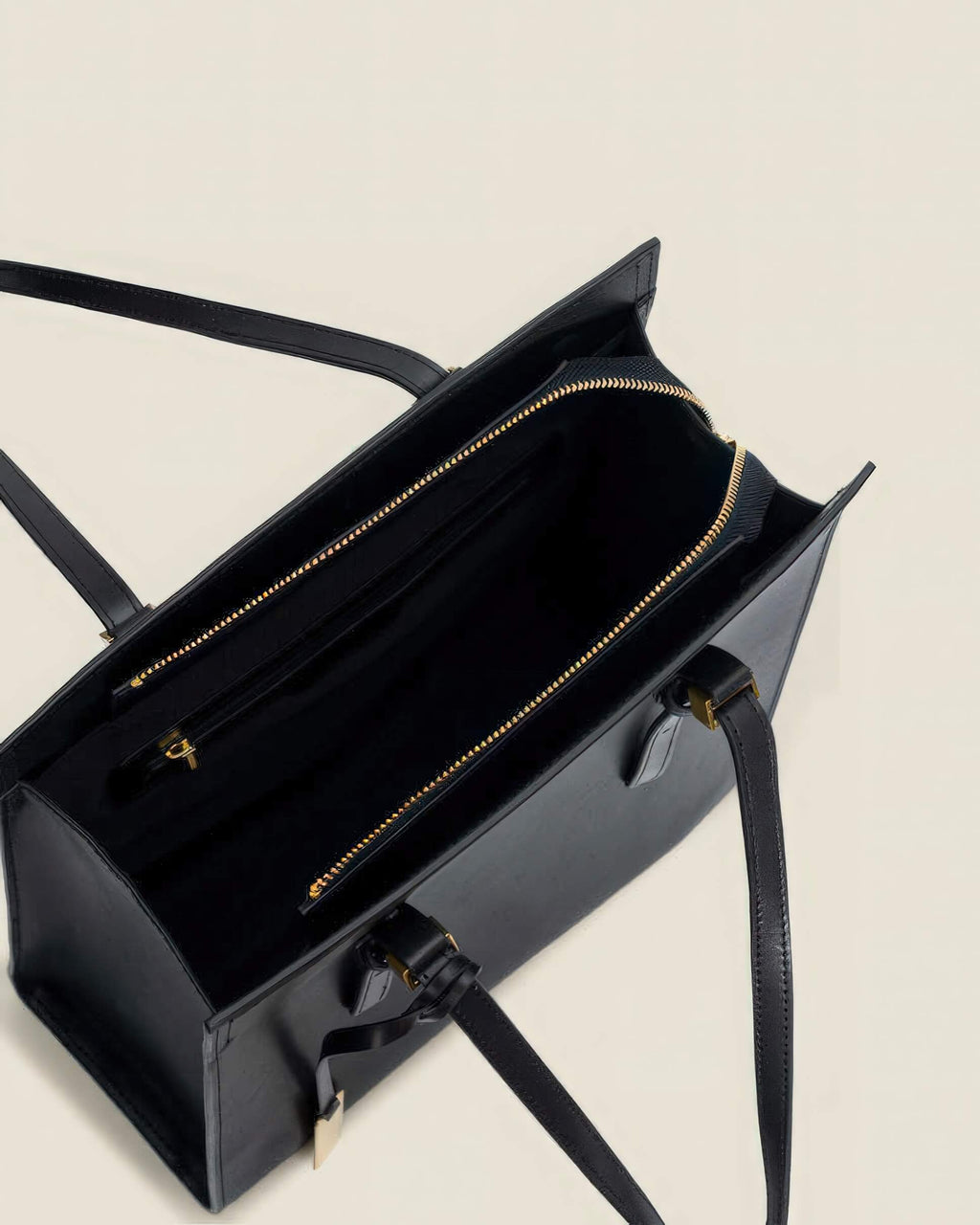 Interior view of a black leather tote bag showing the gold zipper closure and spacious compartments.
