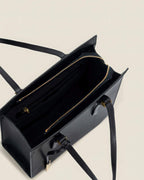 Interior view of a black leather tote bag showing the gold zipper closure and spacious compartments.