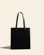 Front view of a sleek black genuine leather tote bag with professional structured design.