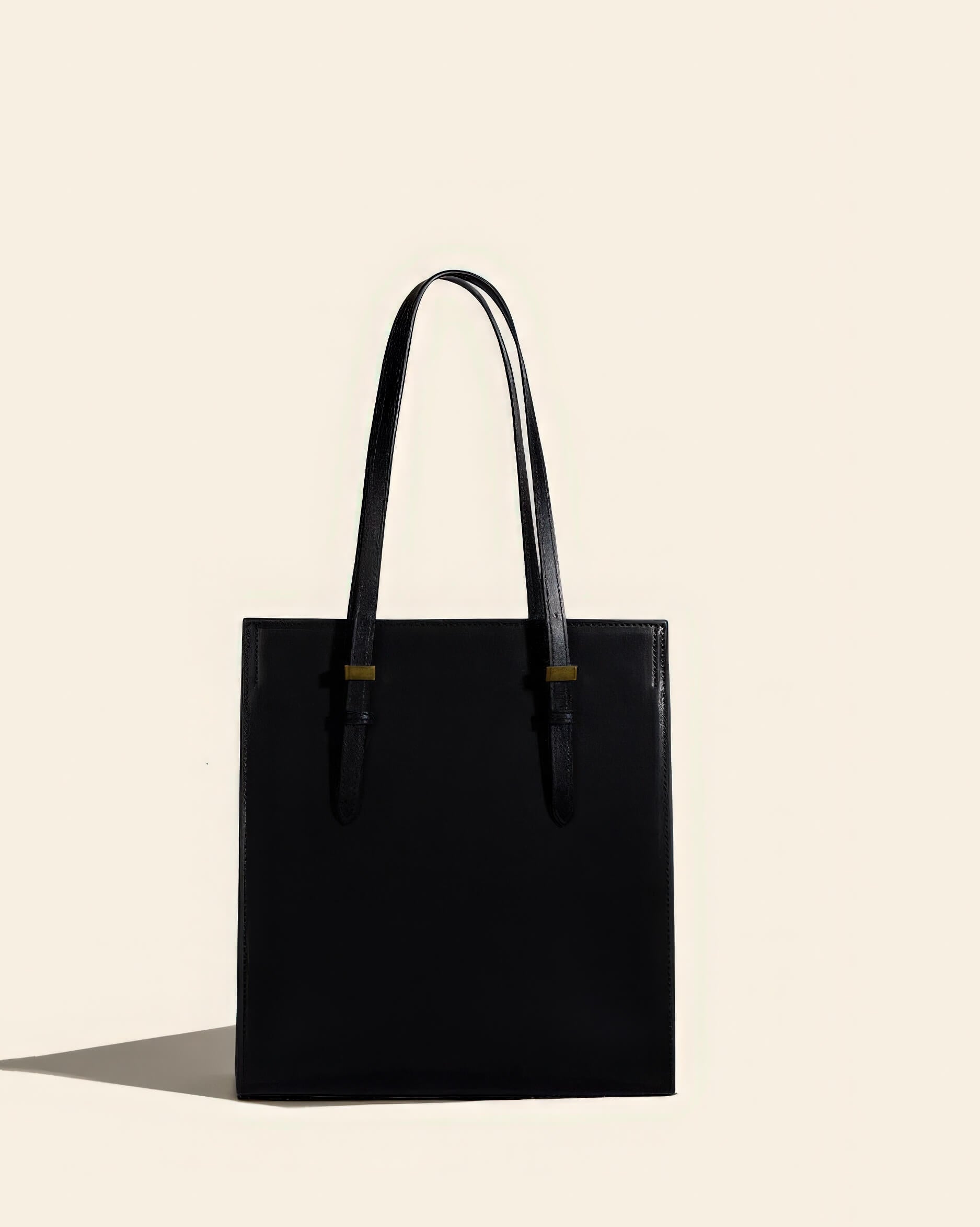 Front view of a sleek black genuine leather tote bag with professional structured design.