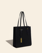 Perspective view of a black leather work tote bag standing upright on a clean background.