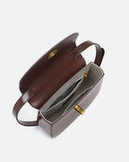 Top-down view into the open interior compartment of a dark brown leather saddle bag showing grey lining and pocket details.