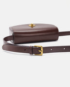 Close-up view of the adjustable leather strap and gold buckle of a dark brown flap saddle crossbody bag.