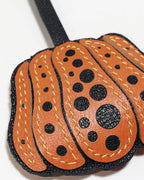 Macro view of detailed stitching and textured French goatskin leather on pumpkin charm.