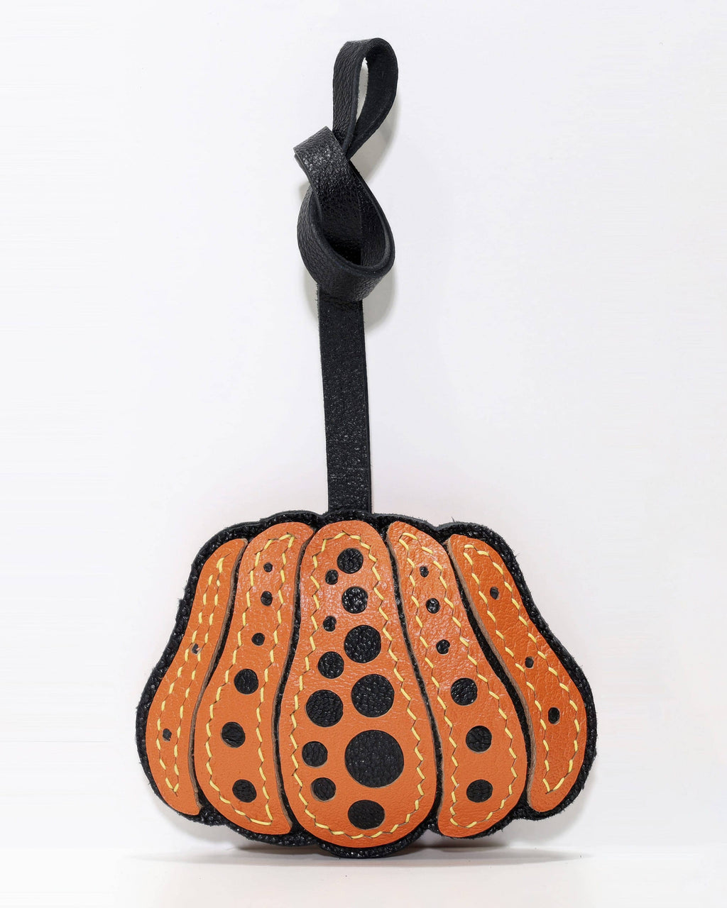 Front view of orange and black polka dot pumpkin leather bag charm with knot strap.