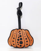 Front view of orange and black polka dot pumpkin leather bag charm with knot strap.