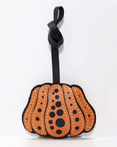 Front view of orange and black polka dot pumpkin leather bag charm with knot strap.