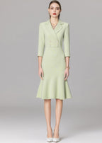 A full-length front view of a model in a mint green double-breasted blazer dress with white pointed-toe heels.