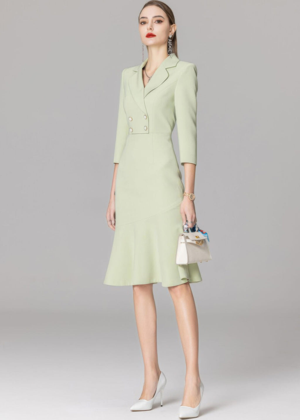A slightly angled full-length view of the model in the light green blazer dress, showcasing the asymmetric seam of the mermaid hem.