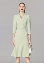 A centered front view of the model in the light green blazer dress, accessorized with a watch, necklace, and small white bag.