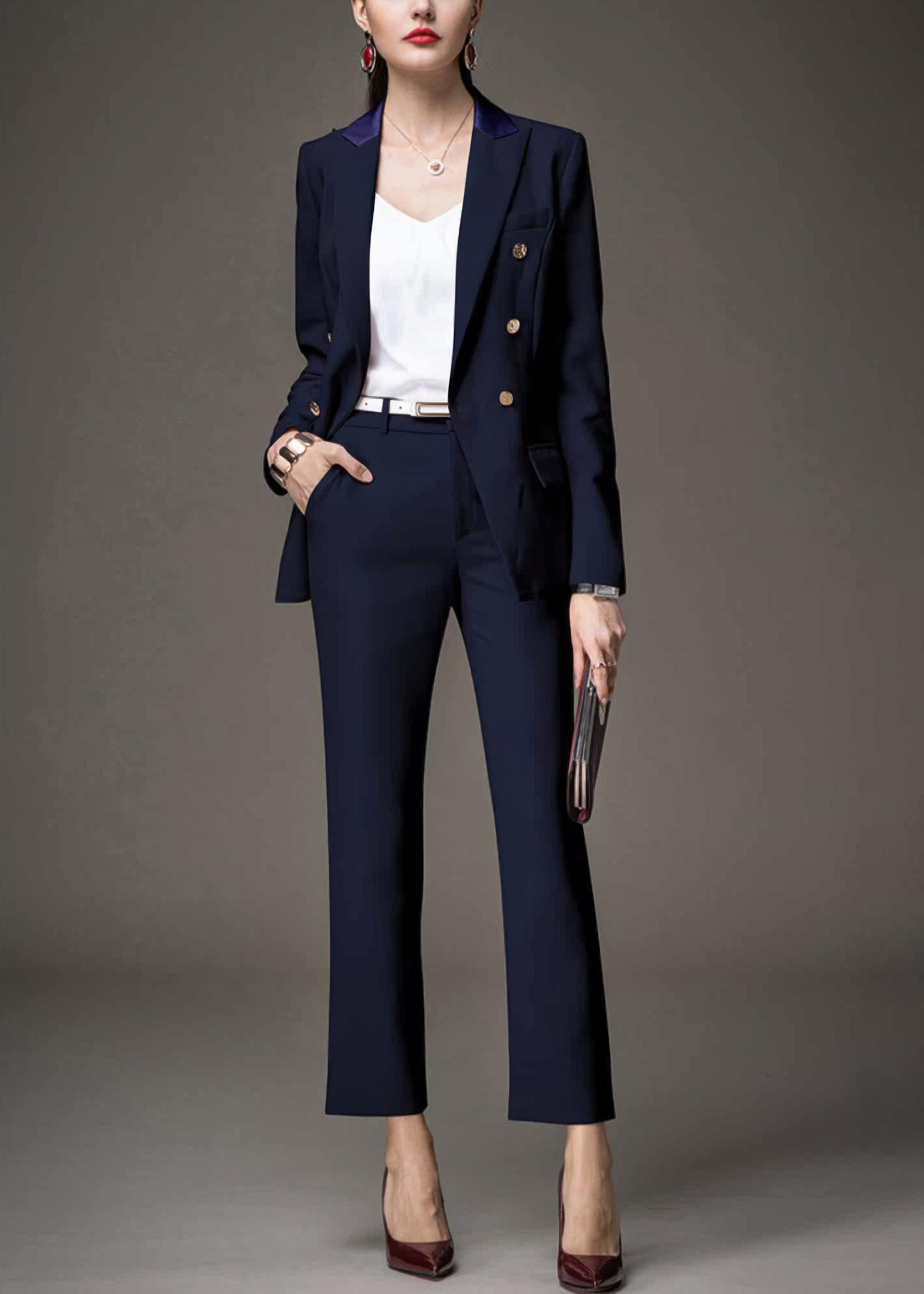 A woman in a navy blue suit with an open blazer, showing a white top and a white belt.