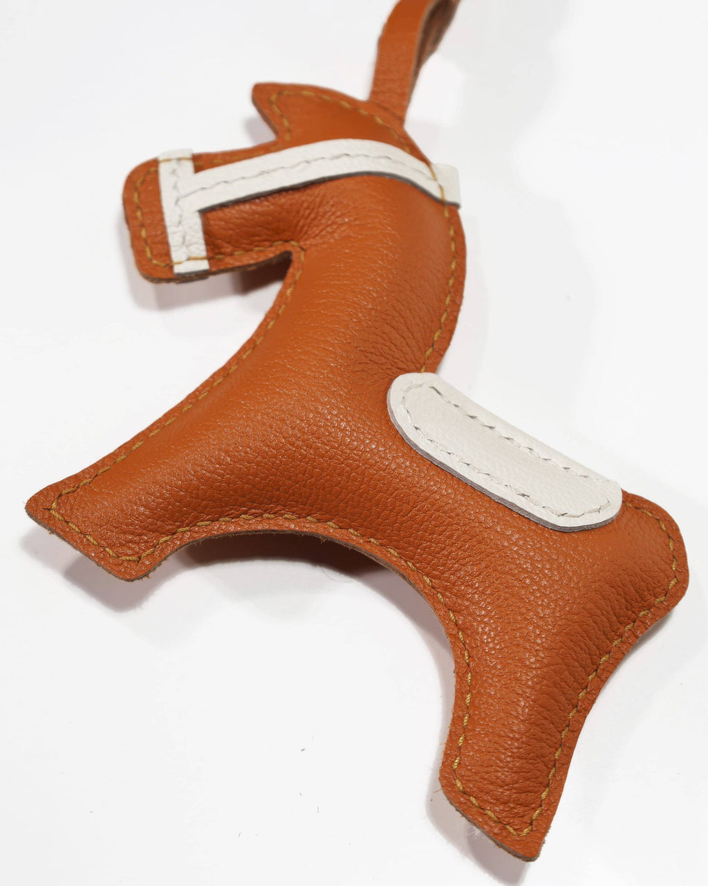 Macro close-up shot highlighting the detailed white leather stitching and premium grain on an equestrian horse bag charm.