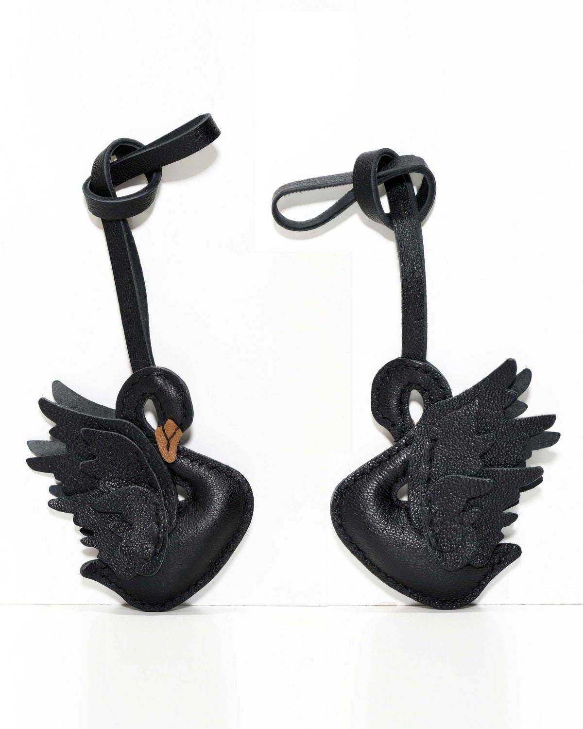 Side-by-side front and back view of black swan leather bag charm.