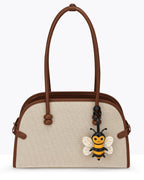 Beige canvas tote bag decorated with a honeybee French goatskin leather bag charm hanging on the strap.