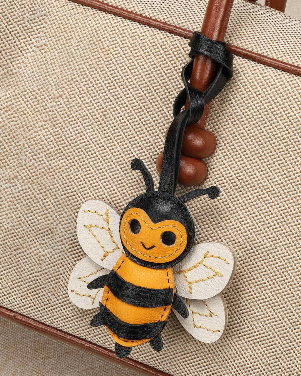 Close-up shot of a cute handcrafted honeybee leather charm attached to a canvas purse handle.