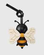 Back view of a honeybee leather bag charm showing yellow stitching on white leather wings and black body.