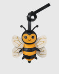 Front view of a cute honeybee leather bag charm with black strap against a studio background.
