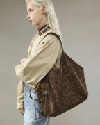Model in casual outfit carrying large brown leopard pattern suede hobo bag with crossed arms pose
