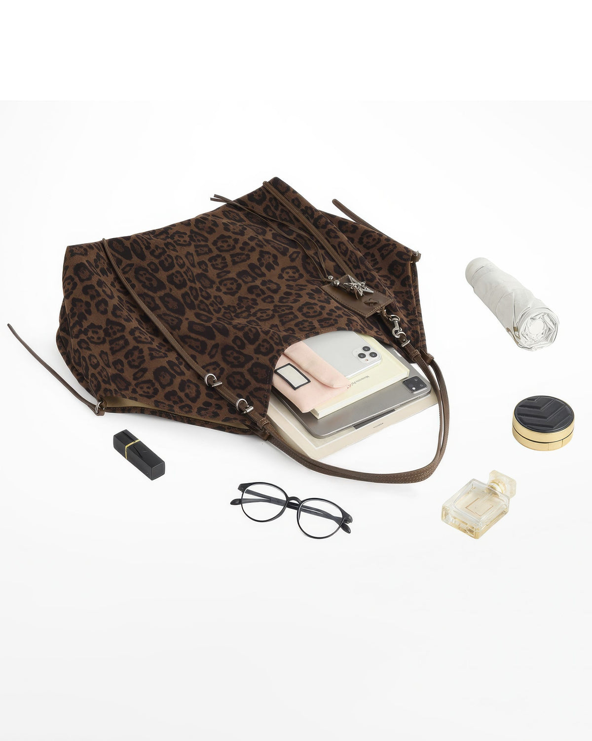 Large capacity flat lay showing open leopard print suede tote filled with tablet, phone, umbrella, glasses, and cosmetics