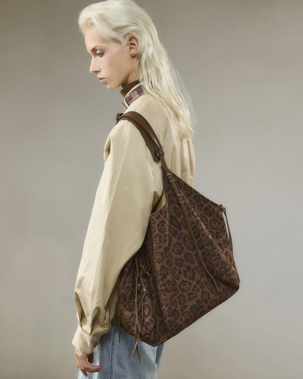 Side view profile of blonde model wearing a slouchy brown leopard print faux suede hobo tote bag over her shoulder