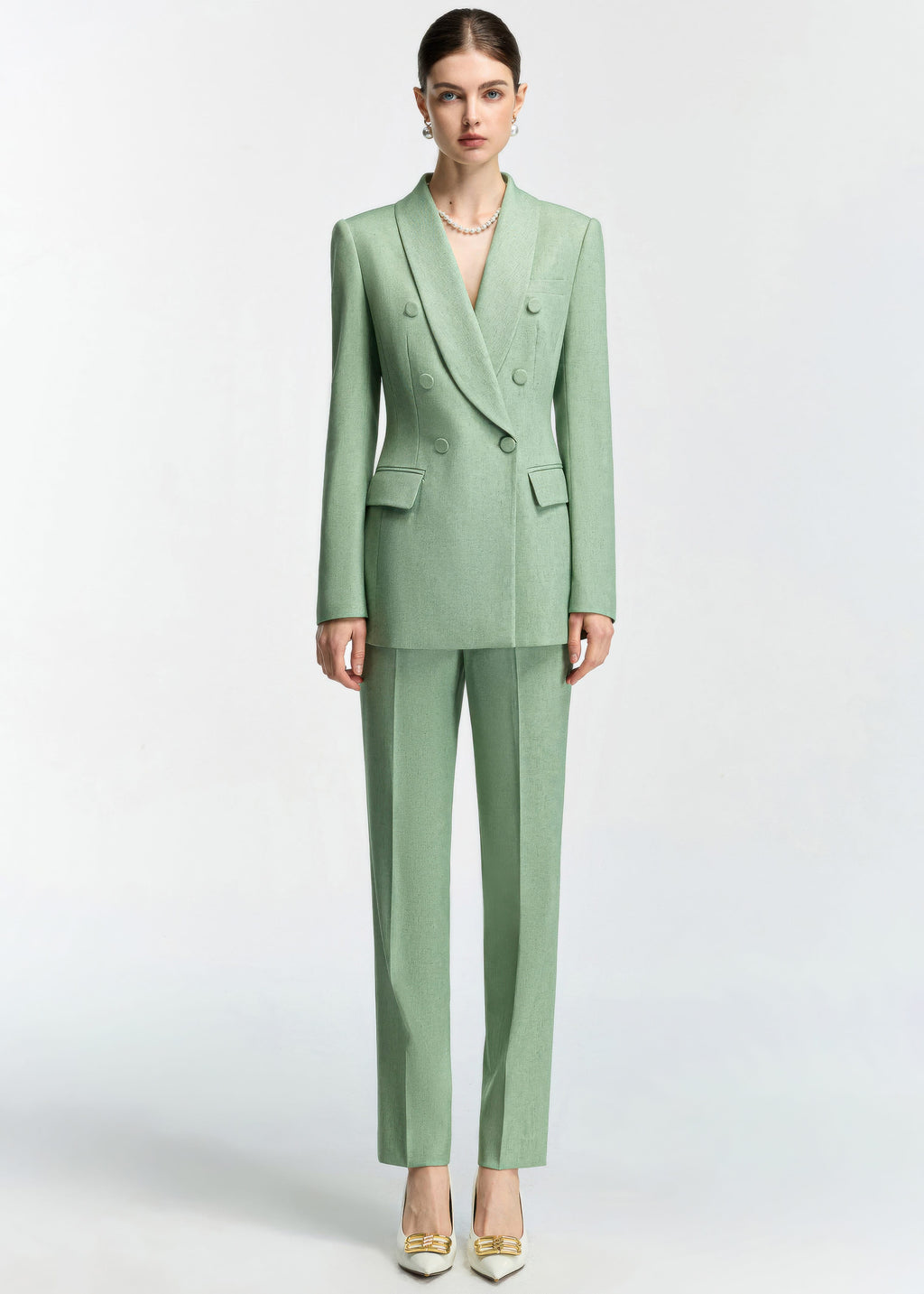 A full-length front view of the model wearing the mint green slim-fit suit with straight-leg trousers and white heels with gold buckle details.