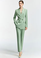 A dynamic full-length shot of the model posing with one hand in her pocket, showcasing the tailored silhouette of the mint green pantsuit.