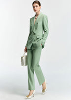 The model is pictured in a walking pose while carrying a white handbag, showing how the slim-fit suit moves.