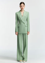 A front-facing full-length shot of a model wearing a mint green double-breasted blazer and matching wide-leg trousers.