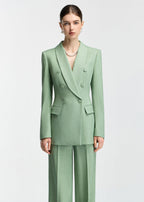 A straight-on studio portrait of the model in the mint green suit, focusing on the structured fit and pearl necklace accessory.