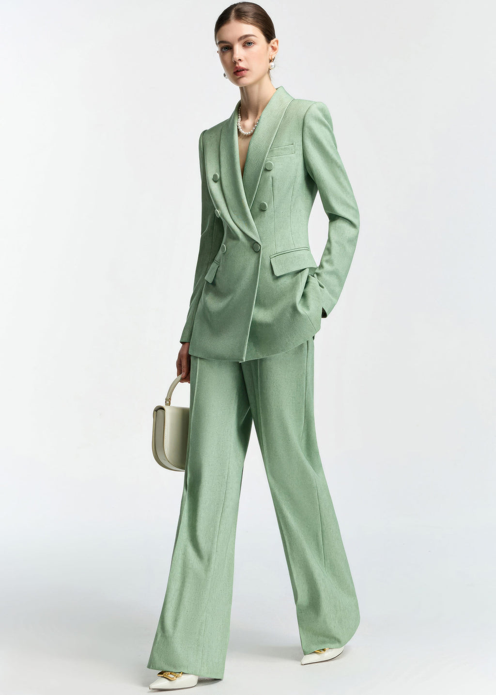 A three-quarter view of the model posing in the mint green suit, highlighting the drape of the wide-leg pants.