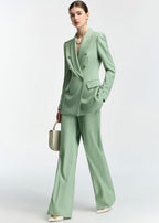 A three-quarter view of the model posing in the mint green suit, highlighting the drape of the wide-leg pants.