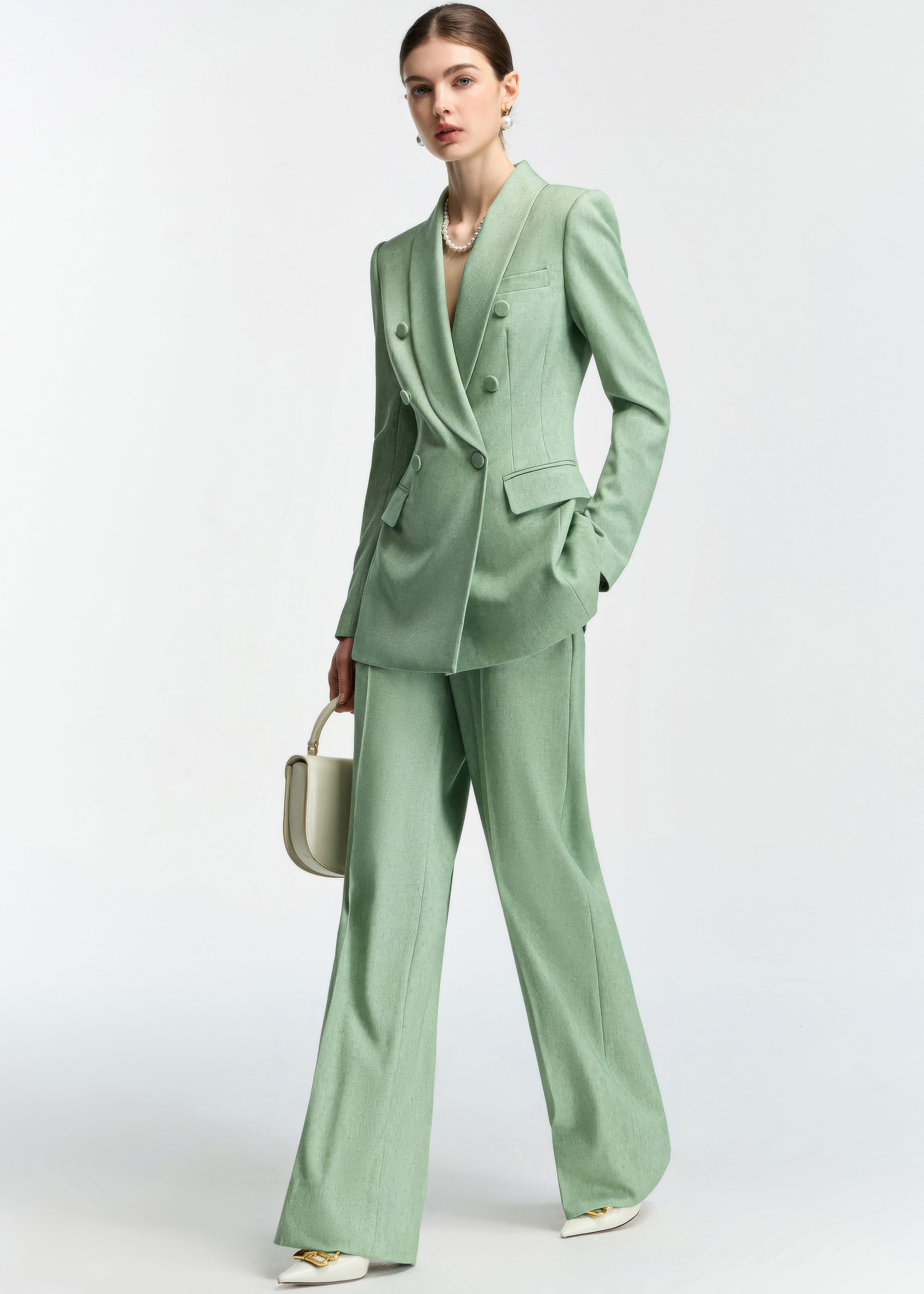 A three-quarter view of the model posing in the mint green suit, highlighting the drape of the wide-leg pants.
