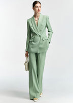 The model is captured mid-stride or posing with a handbag, showing the movement of the mint green suit fabric.