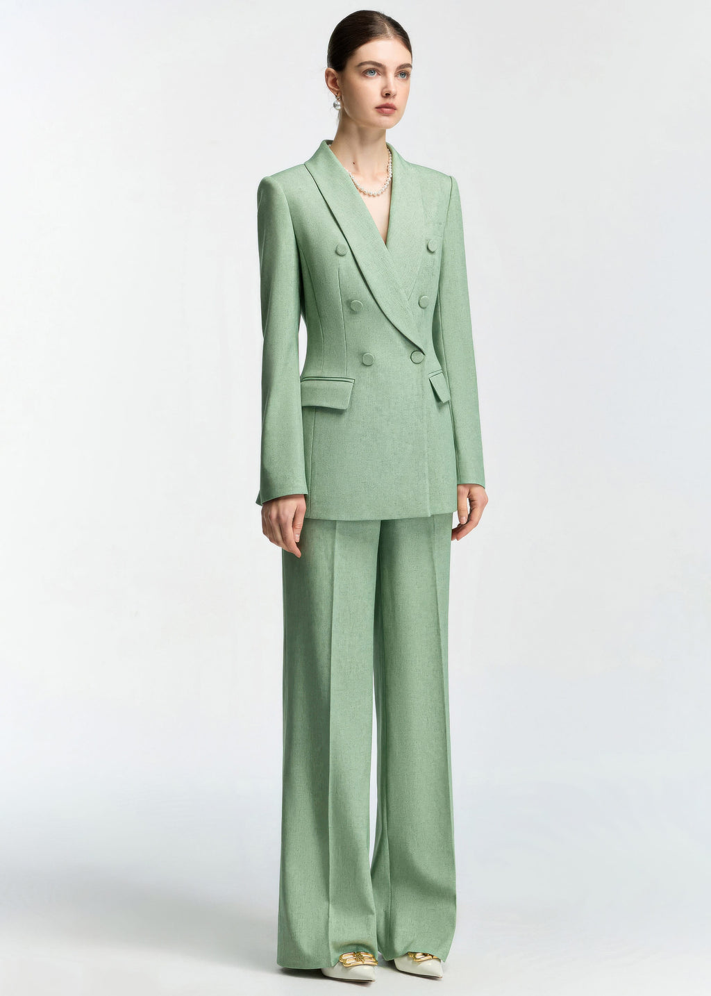 A full-length standing view of the model in the mint green suit against a plain white background.