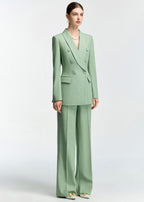 A full-length standing view of the model in the mint green suit against a plain white background.