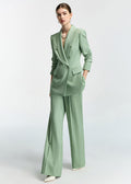 An angled full-length shot of the model with one hand in her pocket, showcasing the suit’s silhouette.