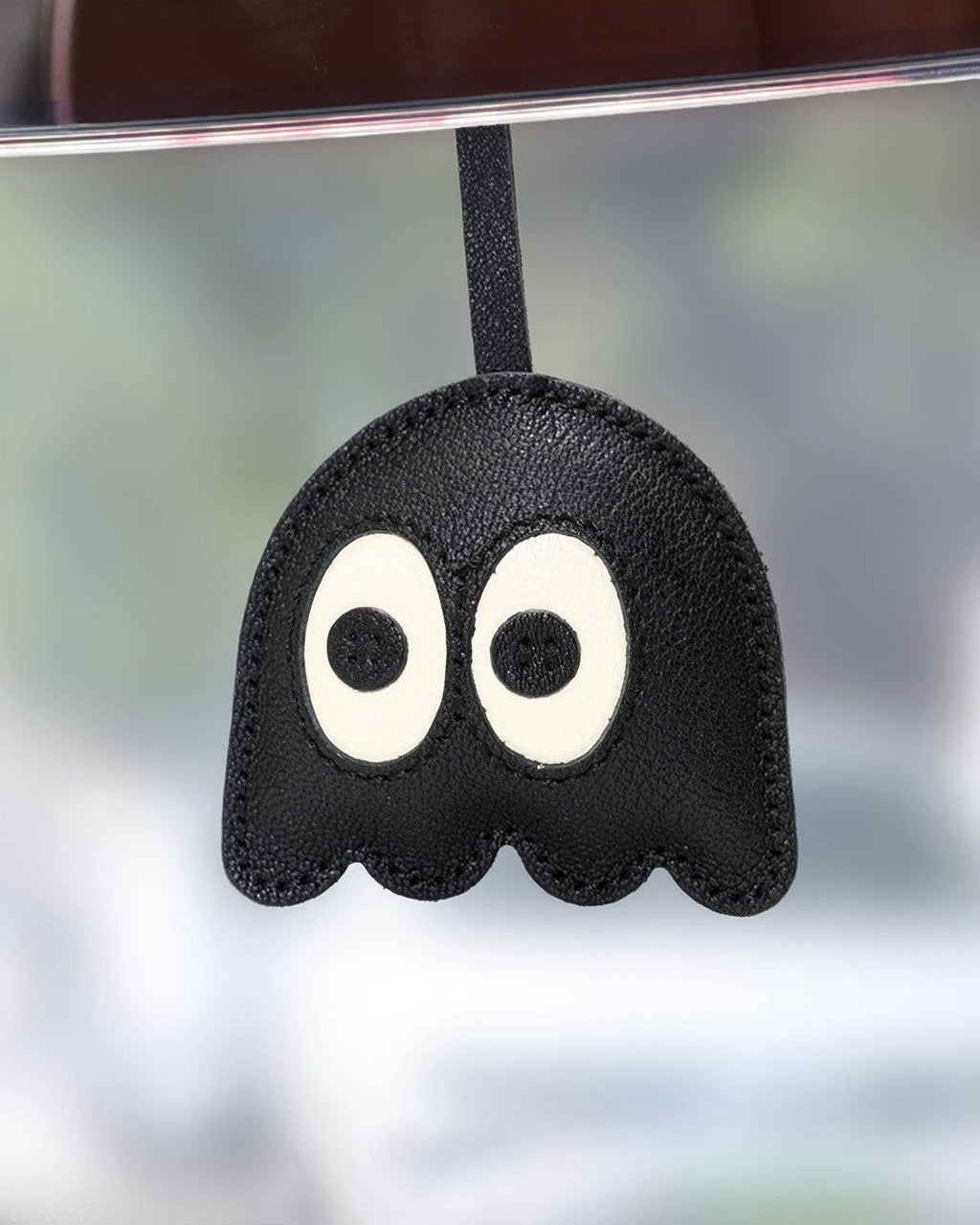 Close-up of black leather ghost charm hanging as a cute car mirror or handbag accessory.
