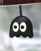 Close-up of black leather ghost charm hanging as a cute car mirror or handbag accessory.
