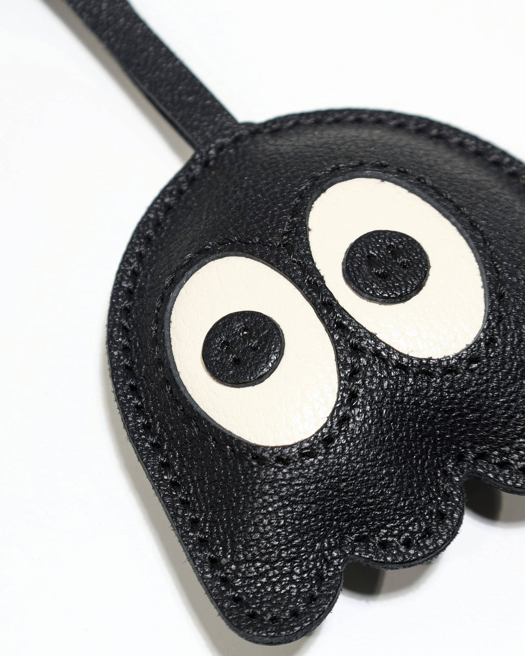 Macro detailed view of textured French goatskin leather and fine stitching on ghost bag charm.