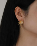 Close-up shot of the Radiant 18K gold burst earring showing its intricate sunburst design and polished gold finish.