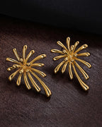 Two Radiant 18K gold plated burst studs placed on a dark wood surface to emphasize the metallic shine.