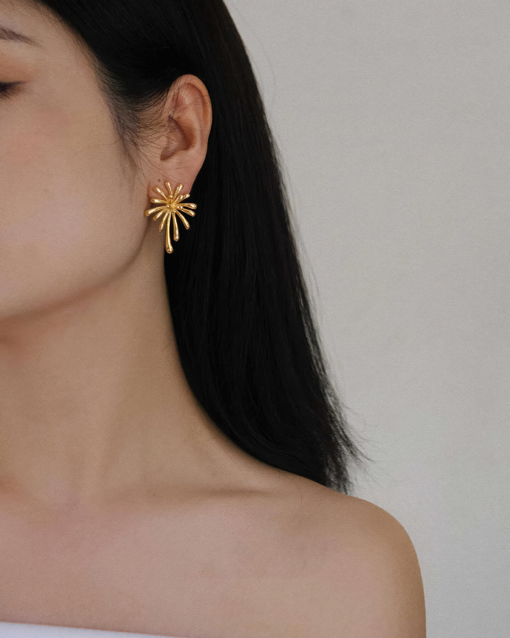 Full view of the gold burst earring on the ear, demonstrating its size and scale as a statement jewelry piece.
