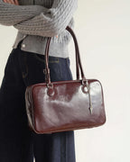 Model holding a dark cherry distressed leather shoulder bag with silver key charm.