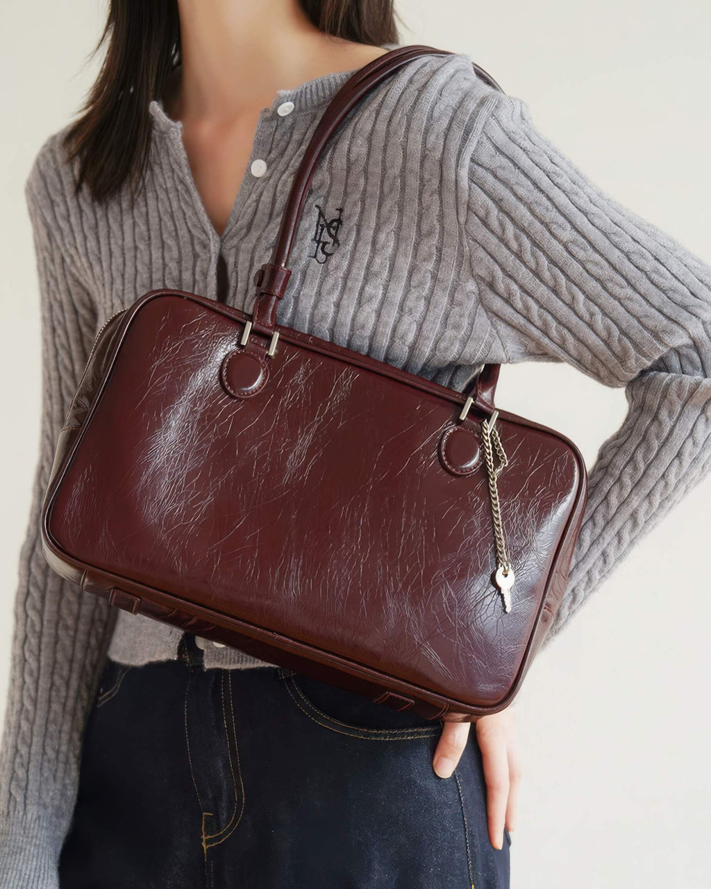 Close up of a luxury deep red wrinkled leather tote bag with elegant silver hardware.