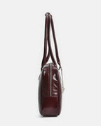 Side profile of a slim burgundy leather satchel showing zipper detail and strap length.