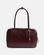 Front view of a rectangular dark red leather shoulder bag with decorative key keychain.